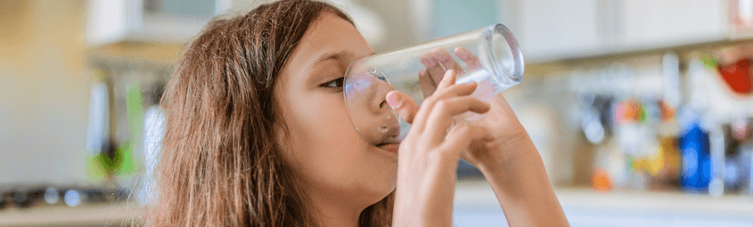 girl drinking glass of water from an Aqua Systems drinking water system